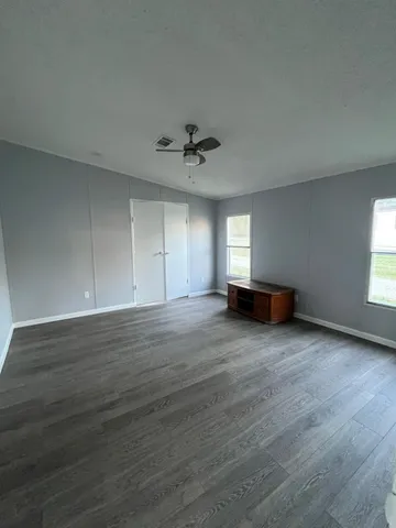 an empty room with wooden floor and ceiling fan