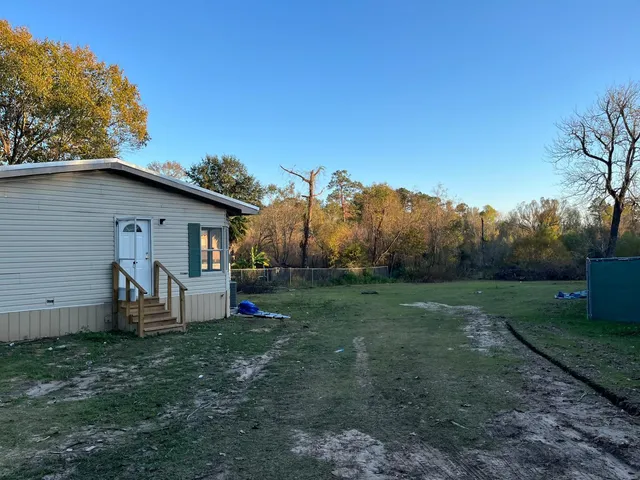 a view of a house with backyard and trees