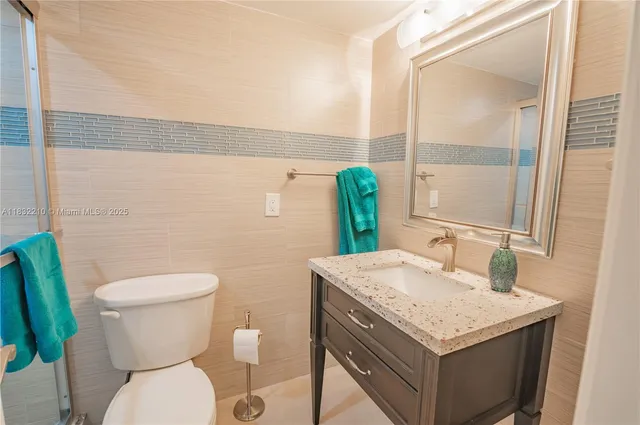 a bathroom with a granite countertop toilet sink and mirror