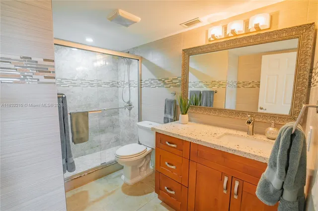a bathroom with a granite countertop sink toilet and shower