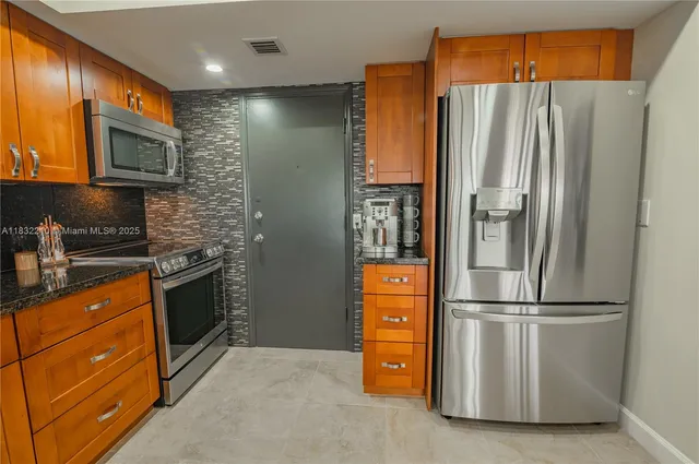 a kitchen with stainless steel appliances granite countertop a refrigerator and a stove top oven