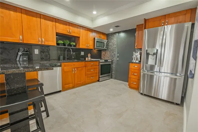 a kitchen with stainless steel appliances granite countertop a refrigerator a stove and a sink with granite countertops