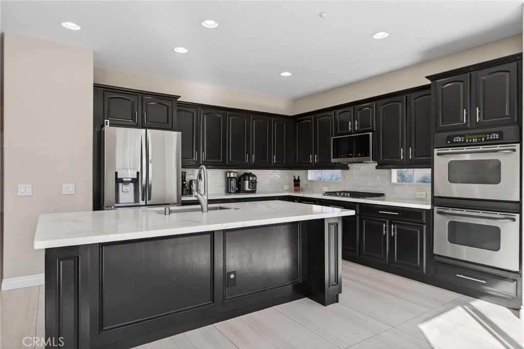 11552 Brookrun Court Riverside, CA 92505 - Photo 11 of 71 a kitchen with kitchen island granite countertop wooden cabinets a stove a oven and a refrigerator with wooden floor