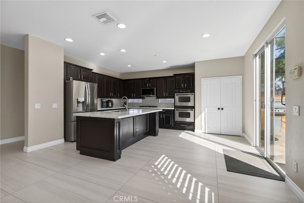 11552 Brookrun Court Riverside, CA 92505 - Photo 13 of 71 a kitchen with stainless steel appliances kitchen island granite countertop a refrigerator and a sink