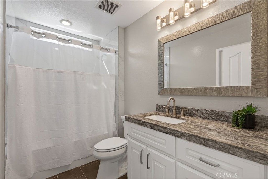 11552 Brookrun Court Riverside, CA 92505 - Photo 20 of 71 a bathroom with a granite countertop sink a toilet and a mirror