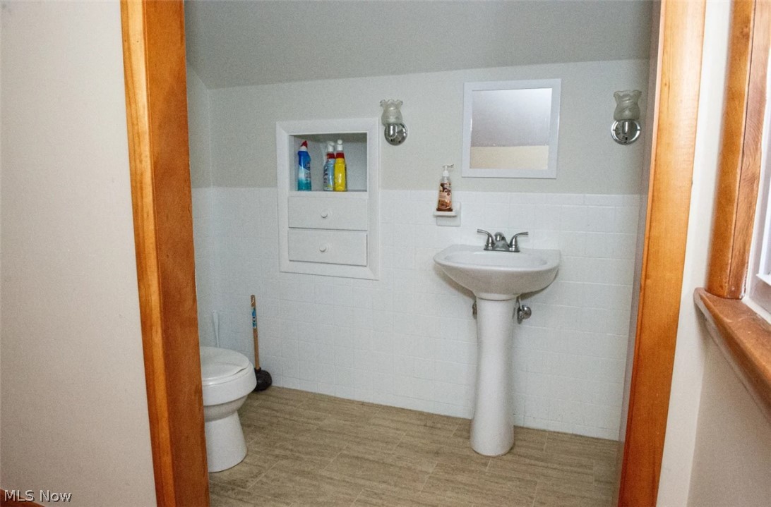 6714 Trenholm Road Youngstown, OH 44512 - Photo 11 of 22 Bathroom with tile walls, tile patterned floors, toilet, and tasteful backsplash