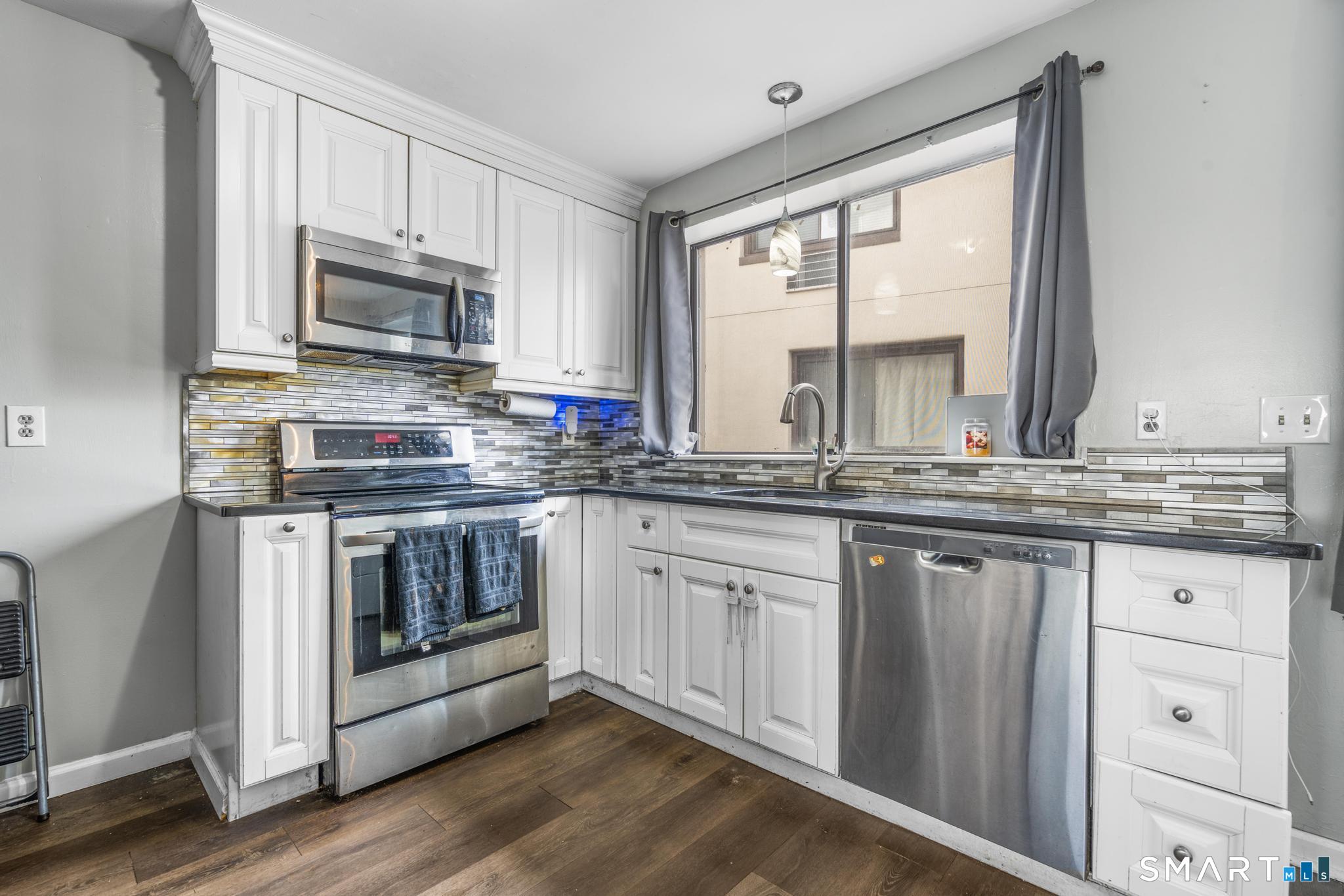 84 Taylor Avenue, Unit 1 Norwalk, CT 06854 - Photo 9 of 40 a kitchen with stainless steel appliances granite countertop a stove a sink and a microwave