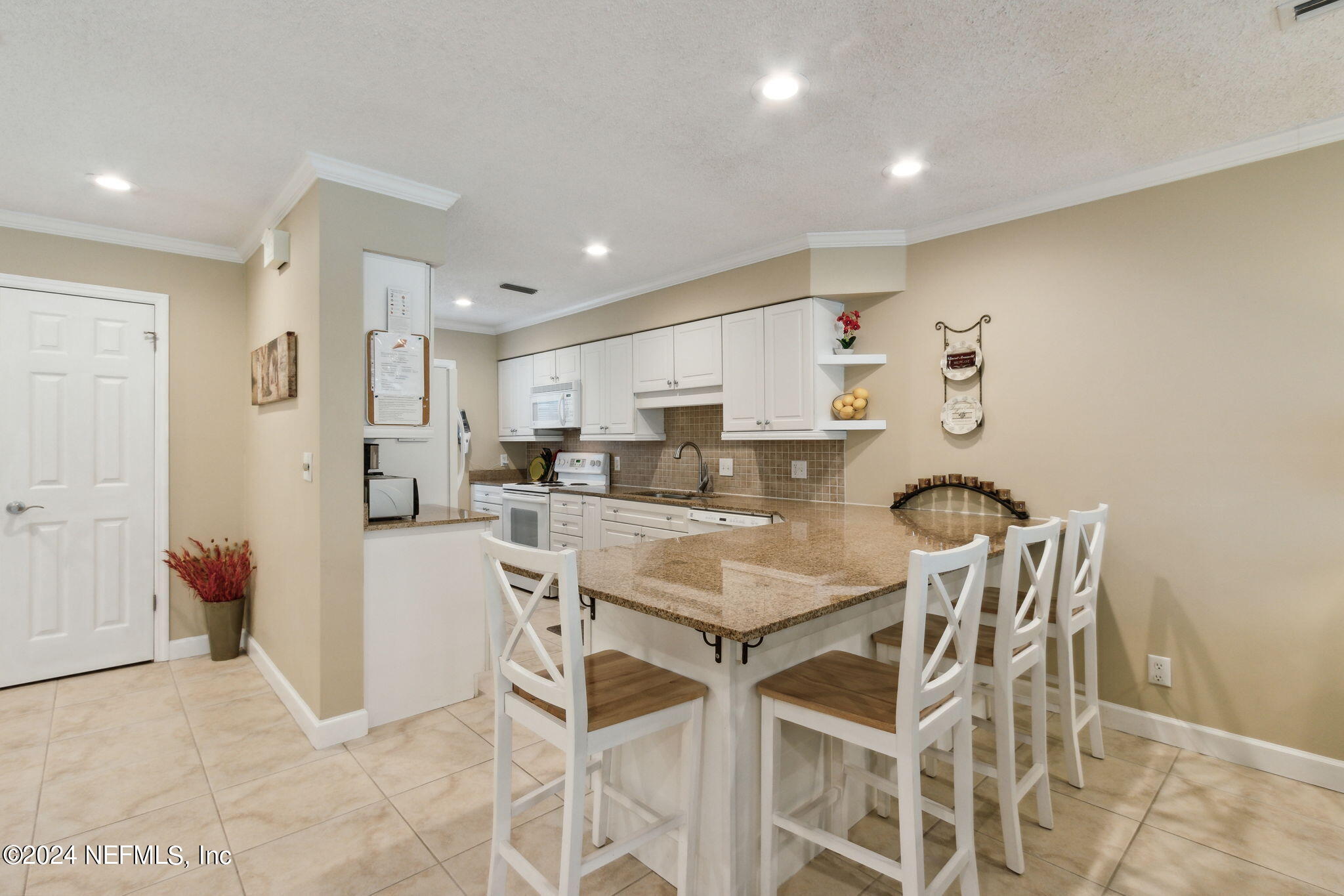3327 Sea Marsh Road Fernandina Beach, FL 32034 - Photo 4 of 39 a kitchen with a dining table chairs refrigerator and cabinets