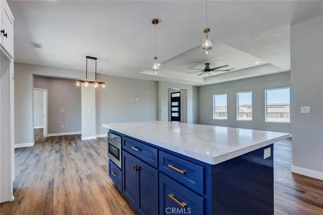 a view of kitchen island a sink wooden floor and a refrigerator