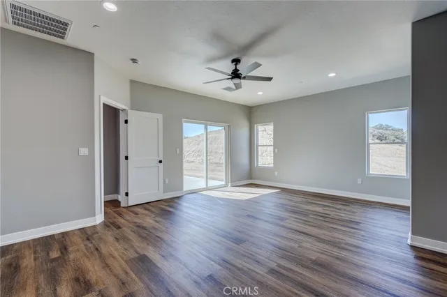 a view of an empty room with window and wooden floor