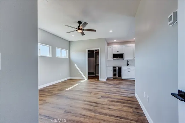 an empty room with wooden floor ceiling fan and windows