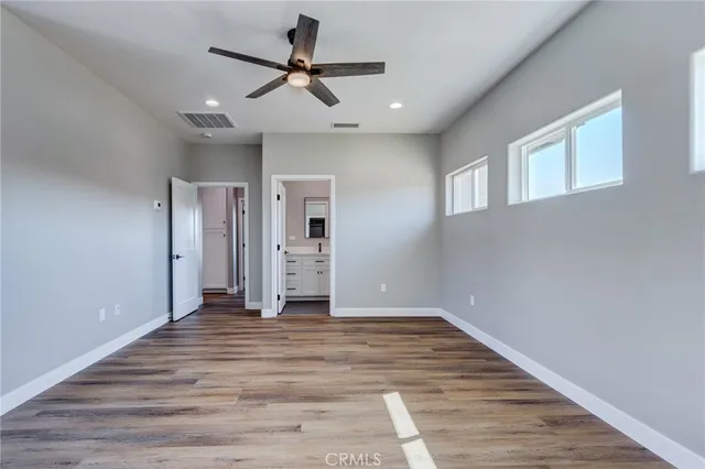 an empty room with wooden floor ceiling fan and windows