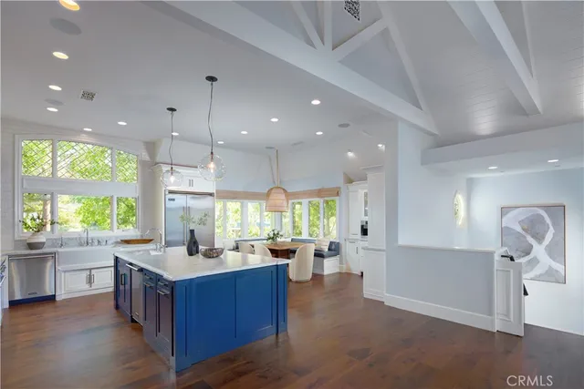 a large kitchen with kitchen island a large counter top a sink stainless steel appliances and cabinets