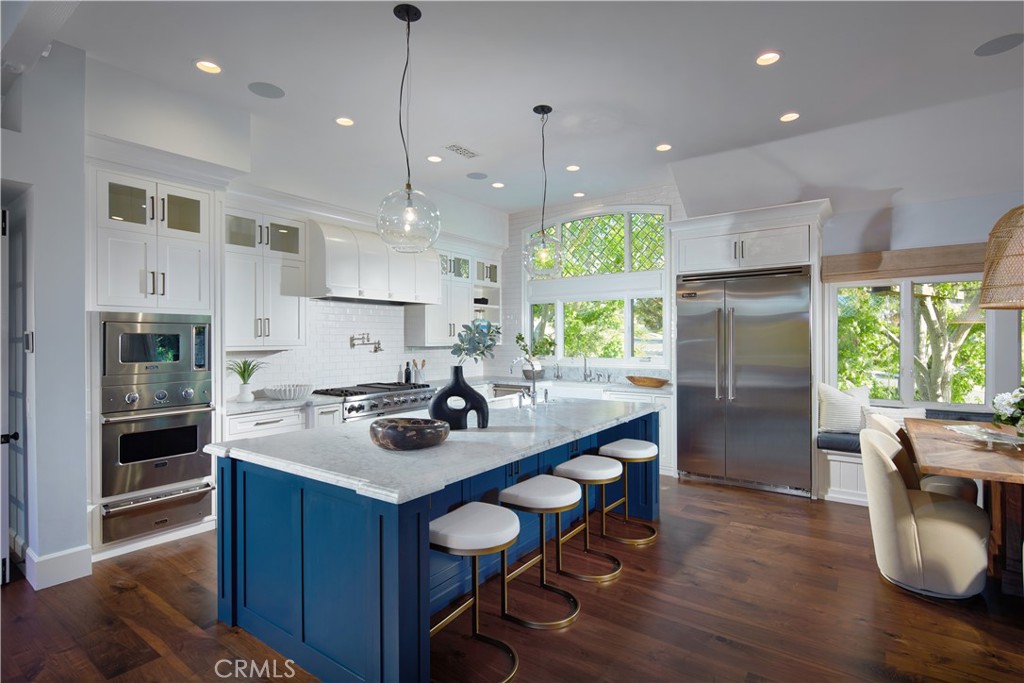 2 Royal St George Road Newport Beach, CA 92660 - Photo 5 of 48 a kitchen with stainless steel appliances granite countertop a sink a stove a refrigerator a kitchen island and chairs with wooden floor