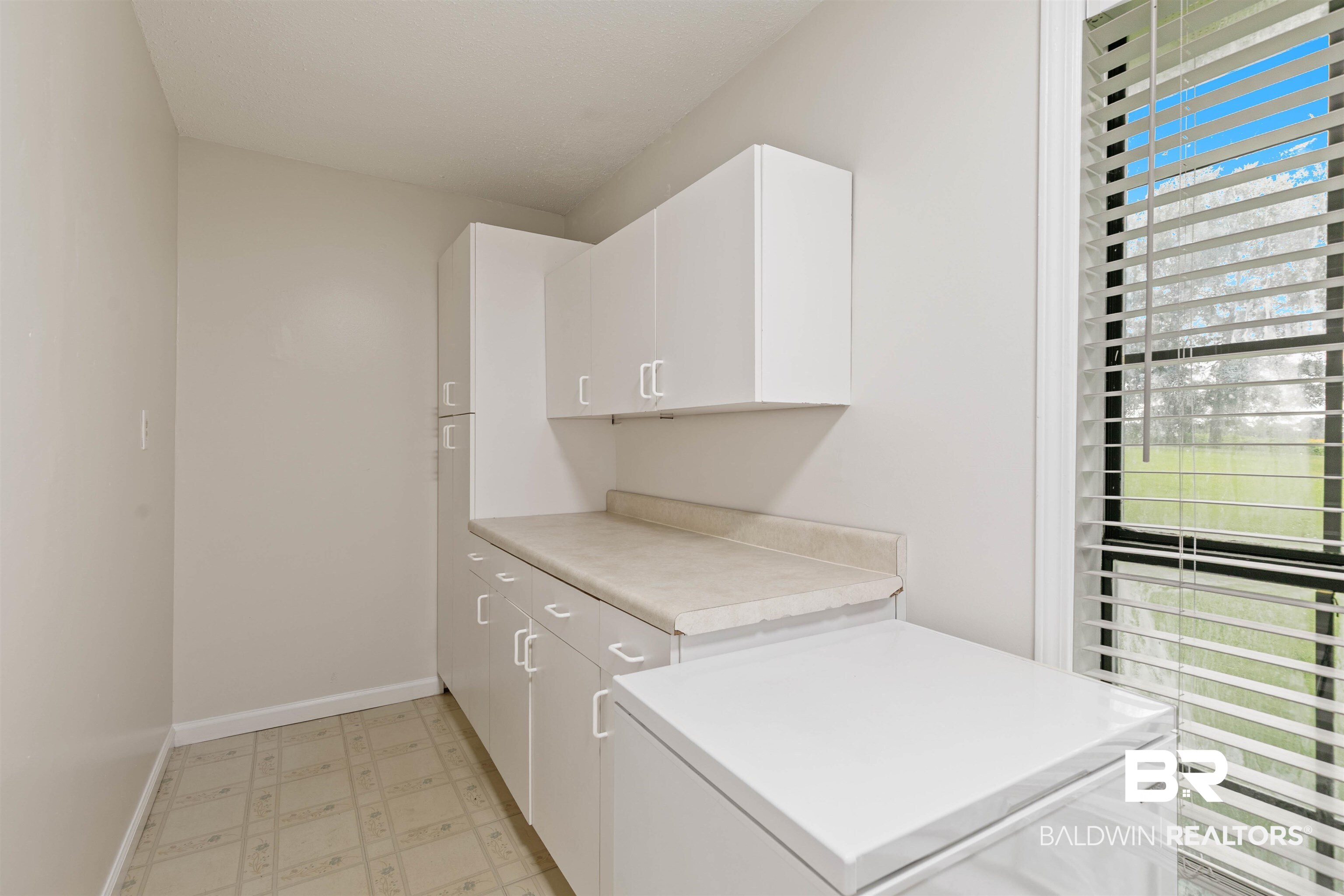 10420 Johnson Road South Mobile, AL 36695 - Photo 47 of 75 Utility room featuring white cabinetry, light-toned countertops, and patterned floor tiling