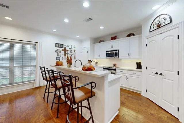 a kitchen with stainless steel appliances a white table and chairs in it