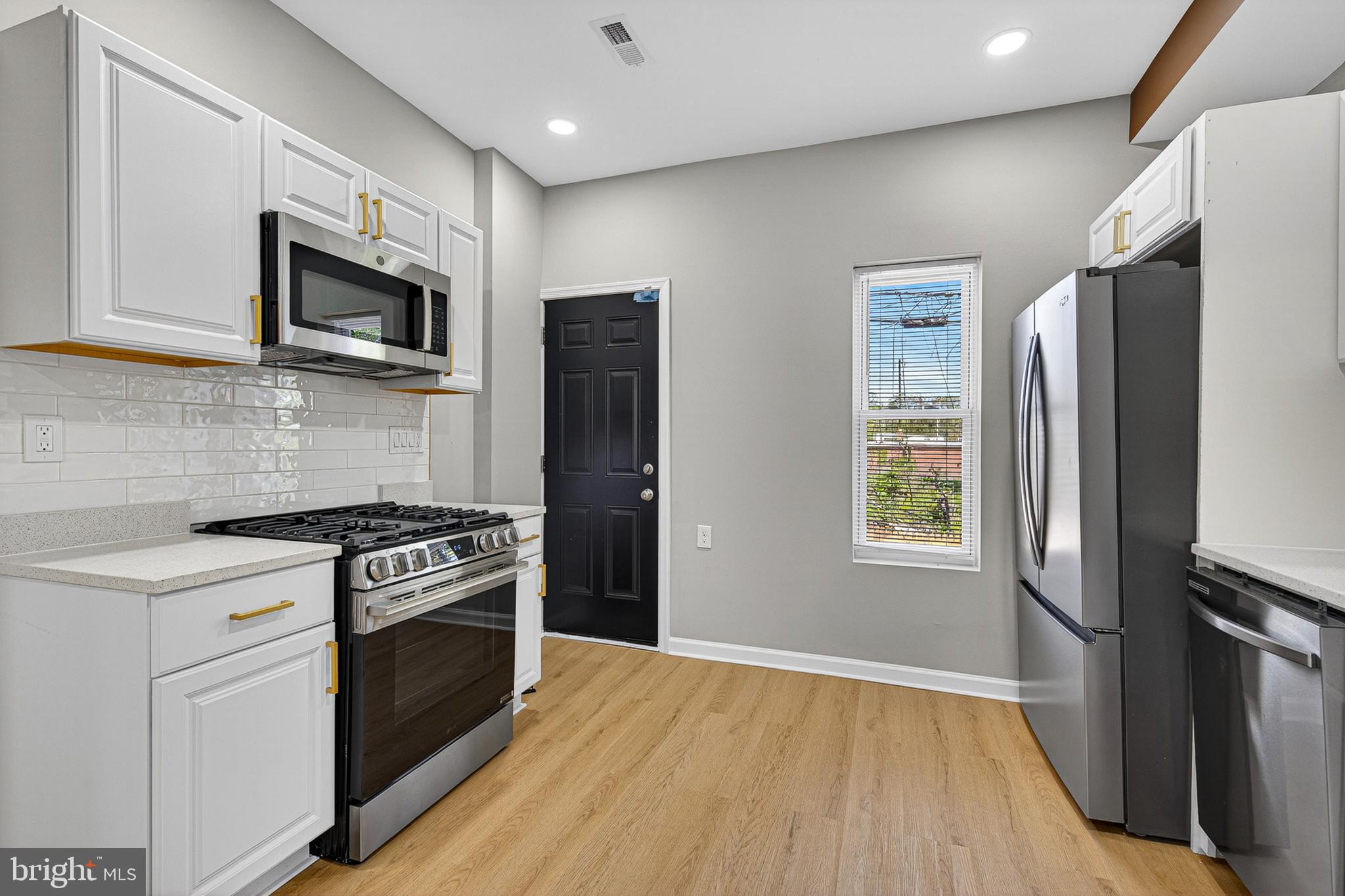 2518 West Fayette Street Baltimore, MD 21223 - Photo 2 of 32 a kitchen with stainless steel appliances a stove a microwave and a refrigerator