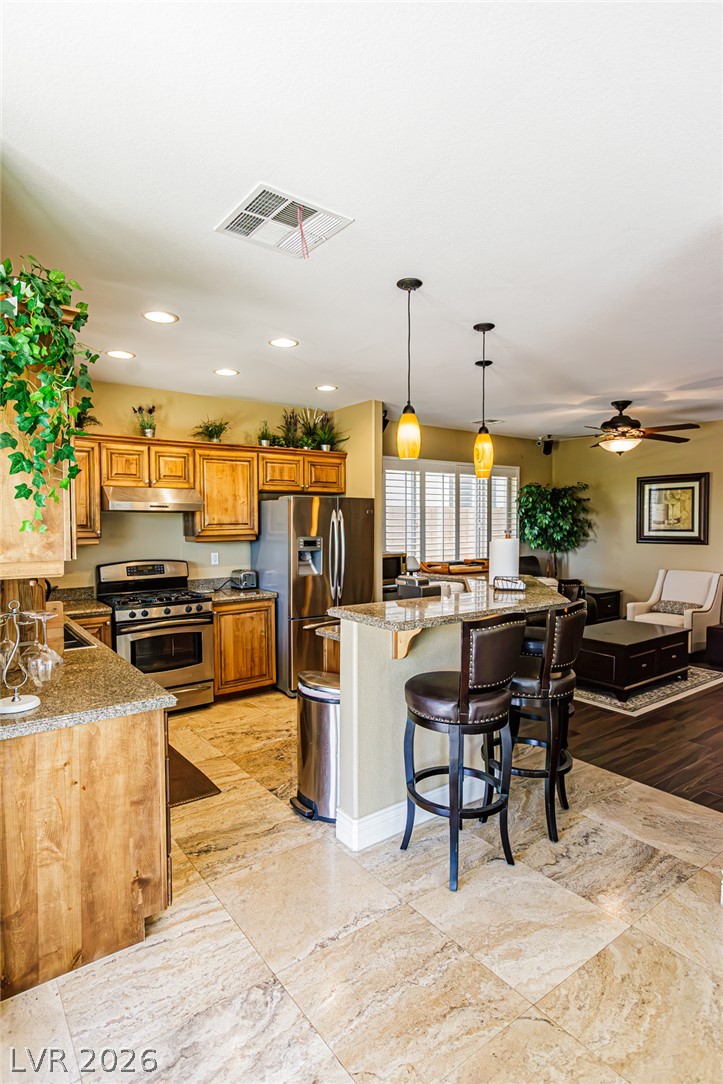 75 Tall Ruff Drive Las Vegas, NV 89148 - Photo 13 of 64 Gleaming stone countertops and warm wood cabinetry anchor this inviting open-concept kitchen.