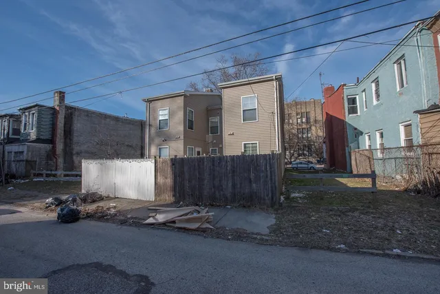 a white house that has a small yard and wooden fence