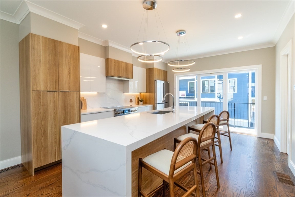 15 Tanglewood Road, Unit A Boston, MA 02126 - Photo 6 of 28 a kitchen with stainless steel appliances a refrigerator a sink dishwasher a dining table and chairs with wooden floor