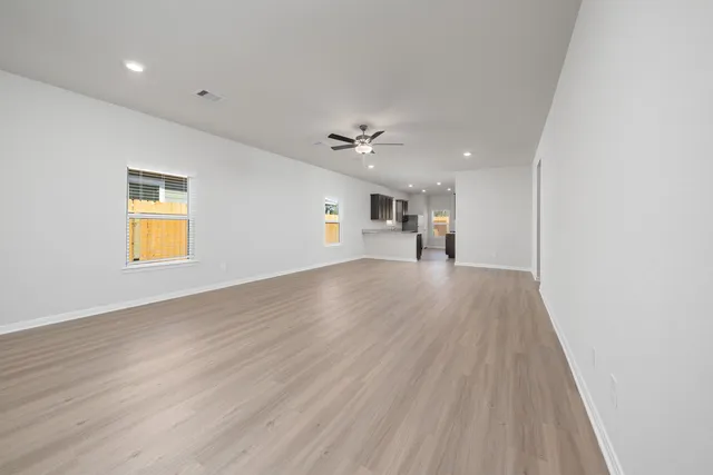 an empty room with wooden floor and a ceiling fan
