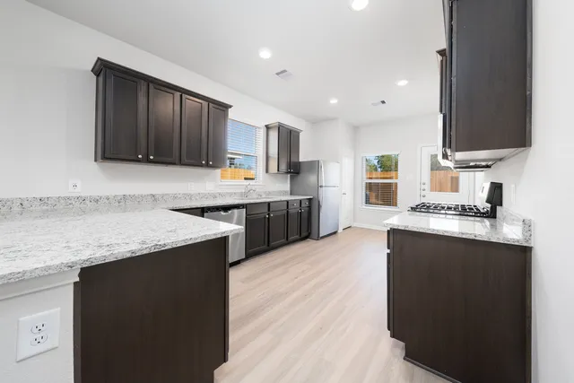 a kitchen with stainless steel appliances granite countertop a sink stove and refrigerator