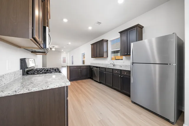 a large kitchen with stainless steel appliances granite countertop a refrigerator a stove and a sink