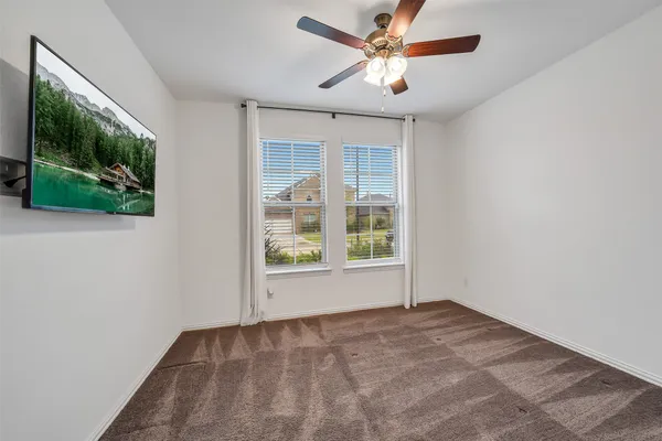 an empty room with windows and ceiling fan
