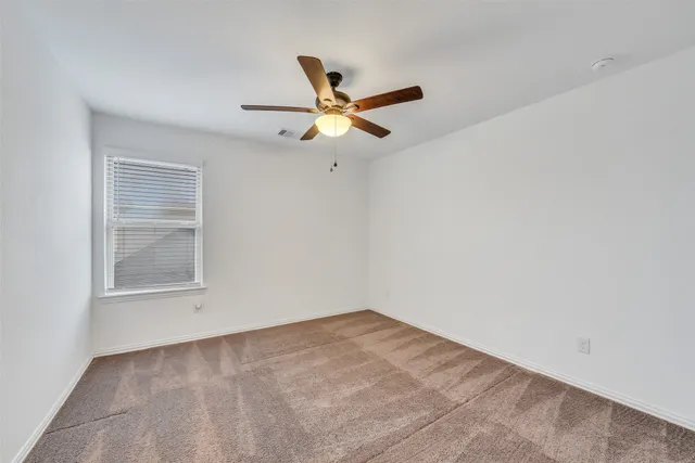 an empty room with a window and a fan