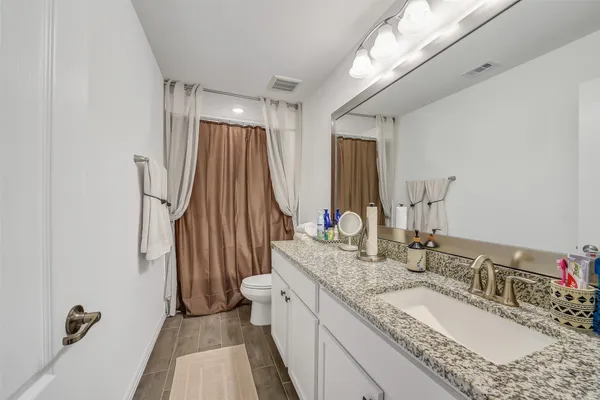 a bathroom with a granite countertop sink a mirror and a shower