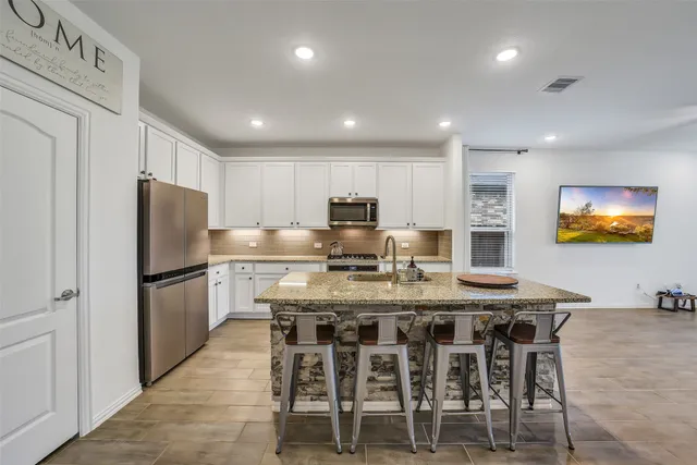 a kitchen with stainless steel appliances granite countertop a table chairs sink refrigerator and microwave