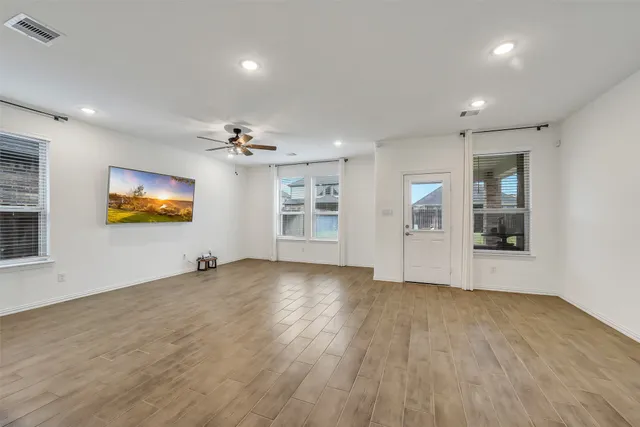 an empty room with wooden floor and windows