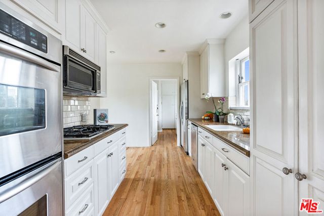 a large kitchen with stainless steel appliances granite countertop a stove and a sink