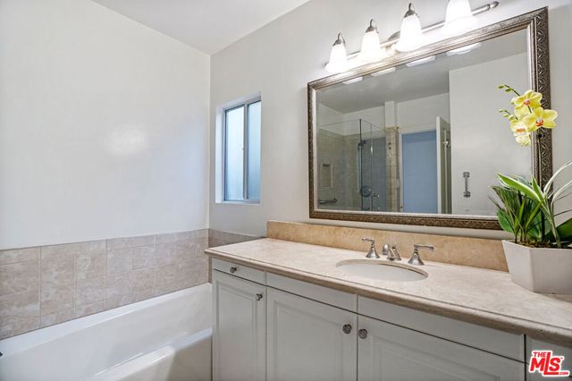 a bathroom with a granite countertop sink a large mirror and a bathtub