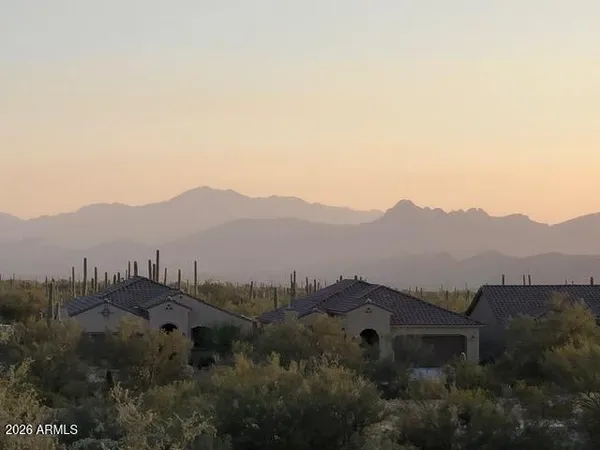 a view of a lush green field with mountains in the background