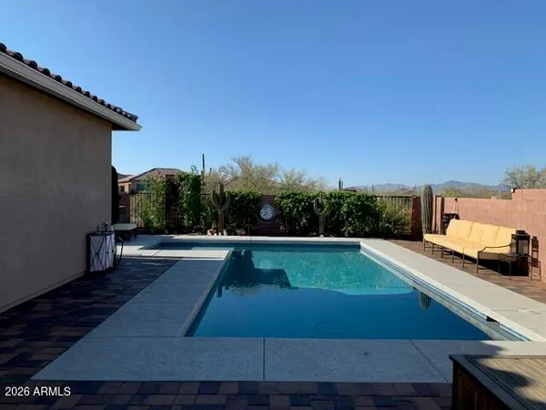 a view of swimming pool with seating area and trees in the background