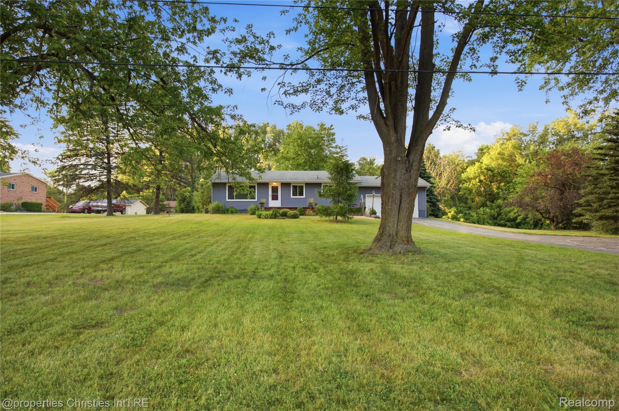 3851 Judd Road Milan, MI 48160 - Photo 41 of 41 Expansive front lawn with mature trees and a paved driveway leading to a two-car garage