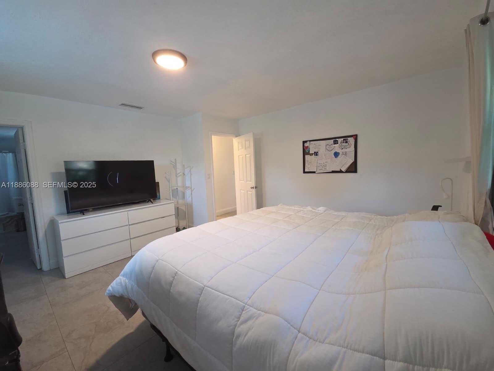 14001 Mustang Trail, Unit 1 Southwest Ranches, FL 33330 - Photo 11 of 31 a bedroom with a large bed and a flat screen tv
