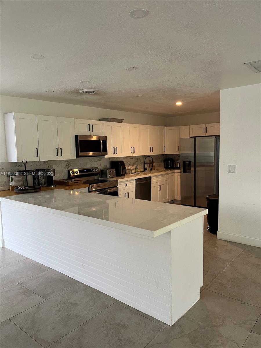 14001 Mustang Trail, Unit 1 Southwest Ranches, FL 33330 - Photo 3 of 31 a large kitchen with stainless steel appliances and a refrigerator