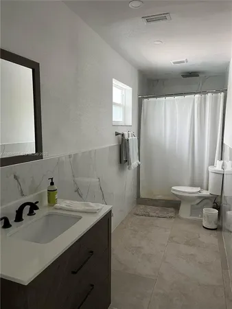 a bathroom with a granite countertop toilet sink and mirror