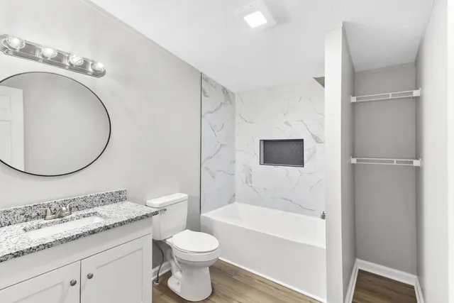 a bathroom with a granite countertop sink toilet a mirror and bathtub