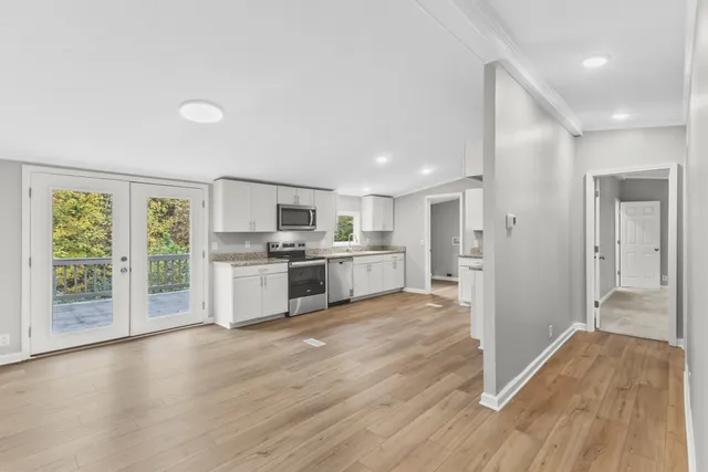 a open kitchen with white cabinets and wooden floor