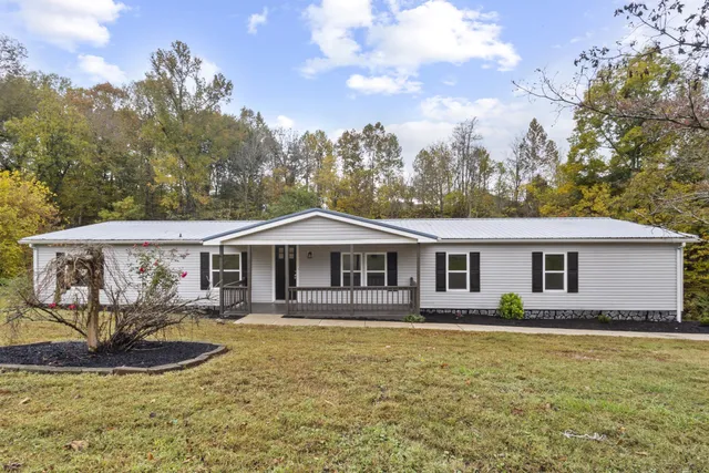 a front view of a house with a yard and trees
