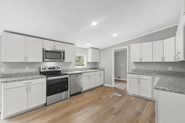 a kitchen with granite countertop appliances cabinets and a sink