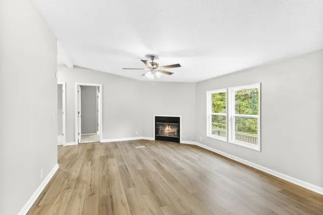 a view of an empty room with a window and wooden floor