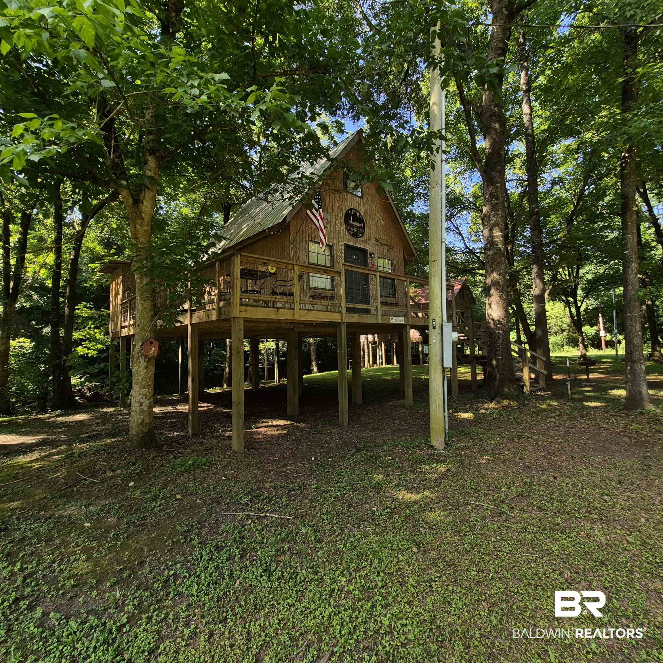 0 Eureka Landing Road Uriah, AL 36480 - Photo 3 of 27 Elevated wood-sided structure featuring a gabled metal roof, exposed support beams, a full-width deck with railing, and multiple windows