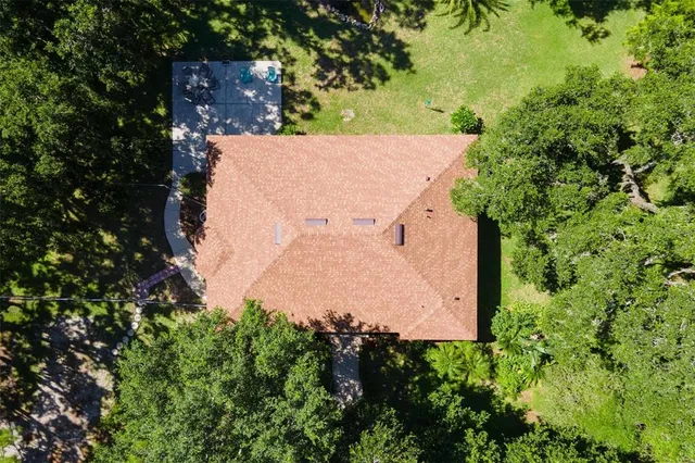 an aerial view of a house with a yard and large trees