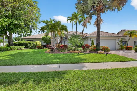 a front view of a house with a garden and palm trees