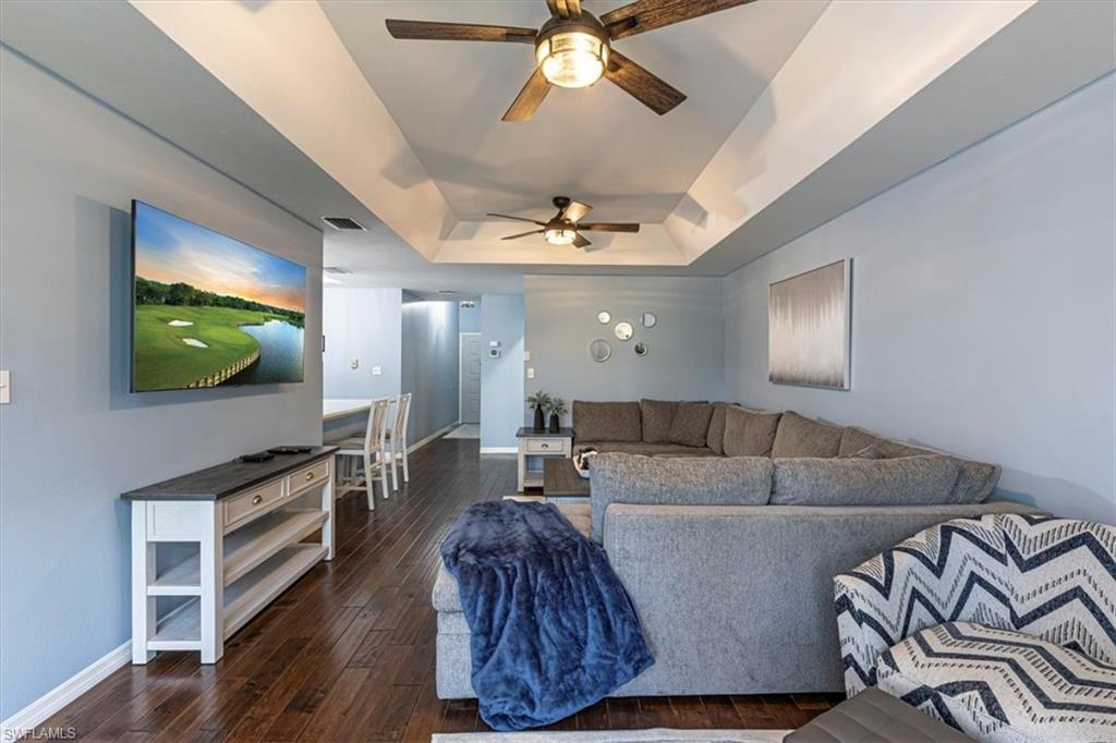 809 Augusta Boulevard, Unit 3 Naples, FL 34113 - Photo 12 of 32 Living room featuring a tray ceiling, dark wood floors, and ceiling fans