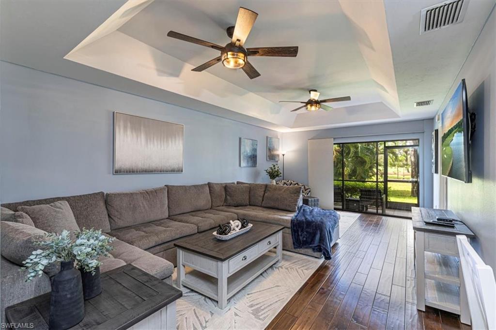 809 Augusta Boulevard, Unit 3 Naples, FL 34113 - Photo 10 of 32 Living room featuring a tray ceiling, dark wood flooring, and ceiling fans